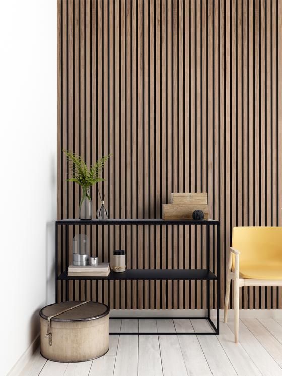 Paneles de pared decorativos de madera, consola negra y silla amarilla en interior moderno