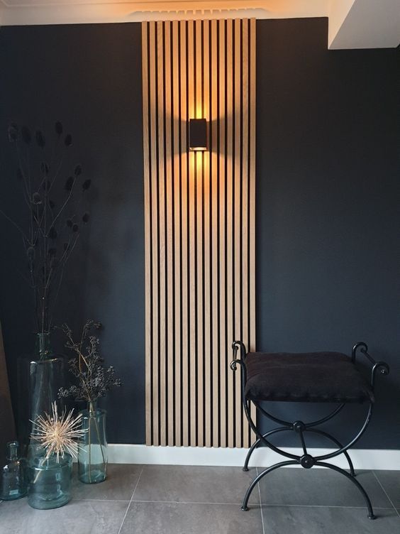 Panel decorativo de listones de madera en pared oscura con aplique de luz y banco moderno