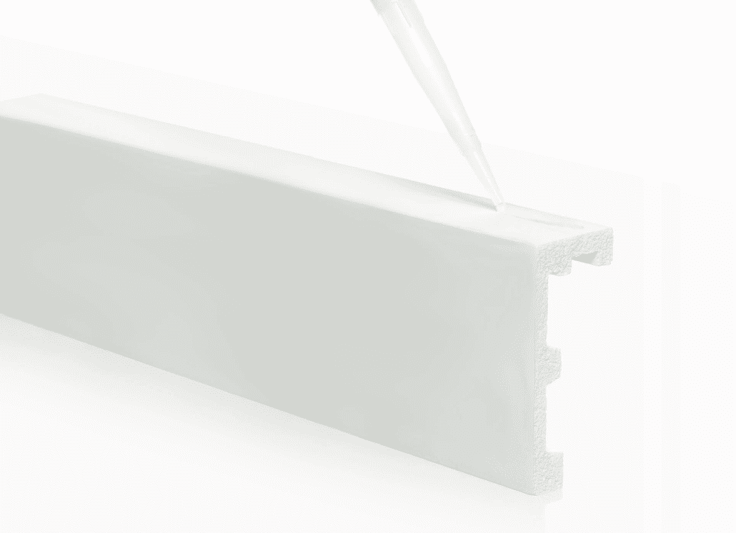 Adhesivo aplicado sobre moldura polimérica blanca decorativa para paredes
