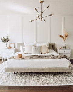 Dormitorio moderno con cabecero tapizado, molduras decorativas blancas y muebles minimalistas.