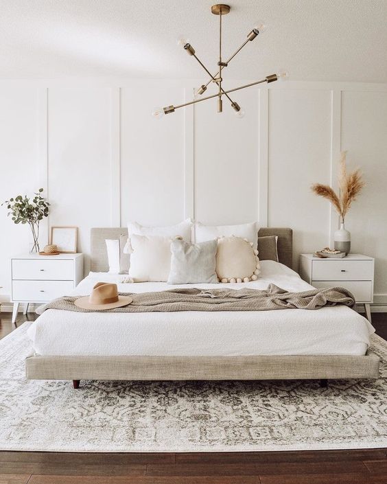 Dormitorio moderno con cabecero tapizado, molduras decorativas blancas y muebles minimalistas.