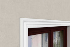 Moldura decorativa blanca instalada sobre marco de ventana, pared beige, acabado elegante
