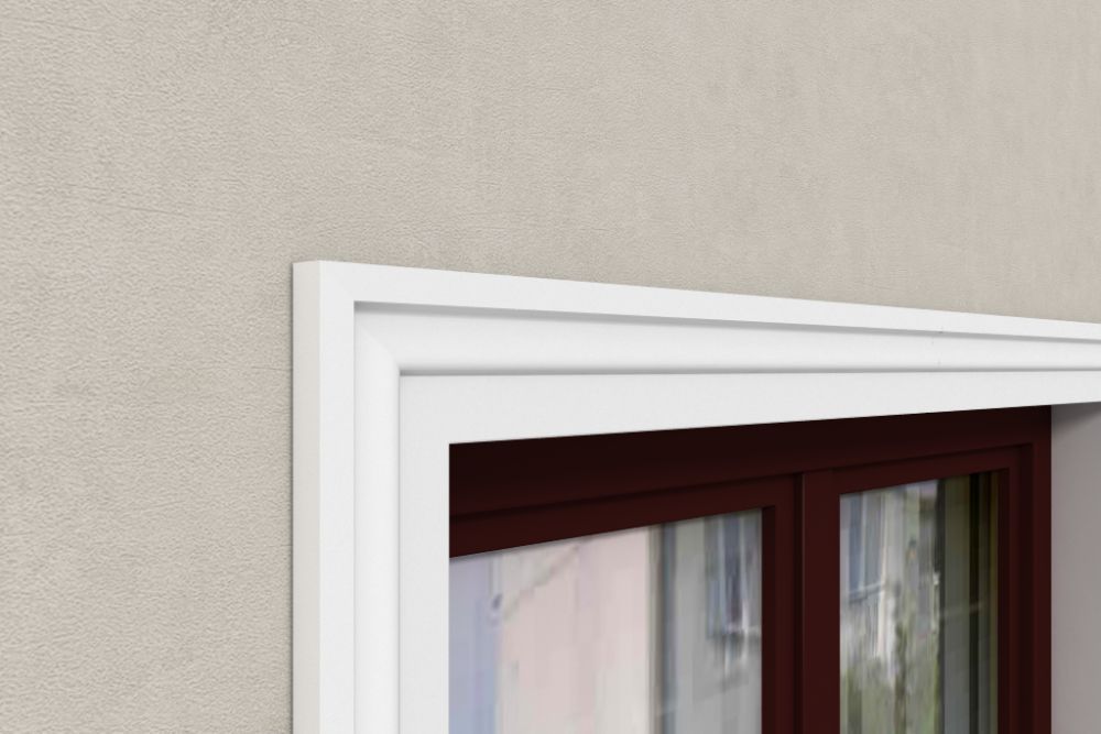 Moldura decorativa blanca instalada sobre ventana de pared beige, ideal para interiores elegantes.