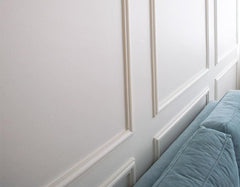 Pared blanca con molduras decorativas tipo cuarterones y sofá azul claro