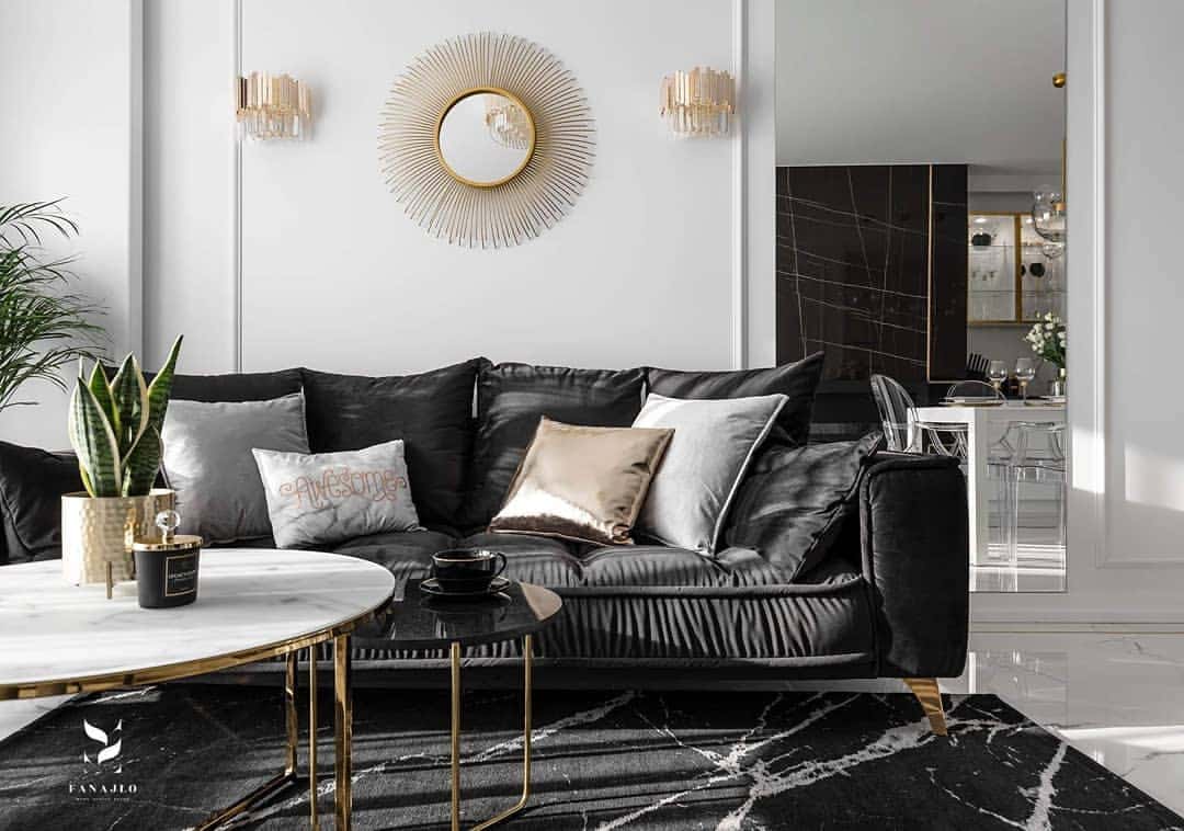 Sala moderna con sofá negro, molduras decorativas en pared blanca y mesa de centro elegante