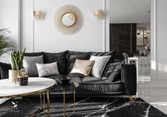 Sala moderna con sofá negro, molduras decorativas en pared blanca y mesa de centro elegante