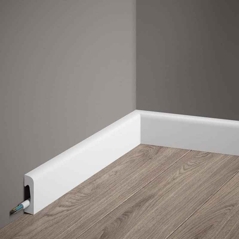 Rodapié blanco moderno con canal para cables en pared gris y suelo de madera.