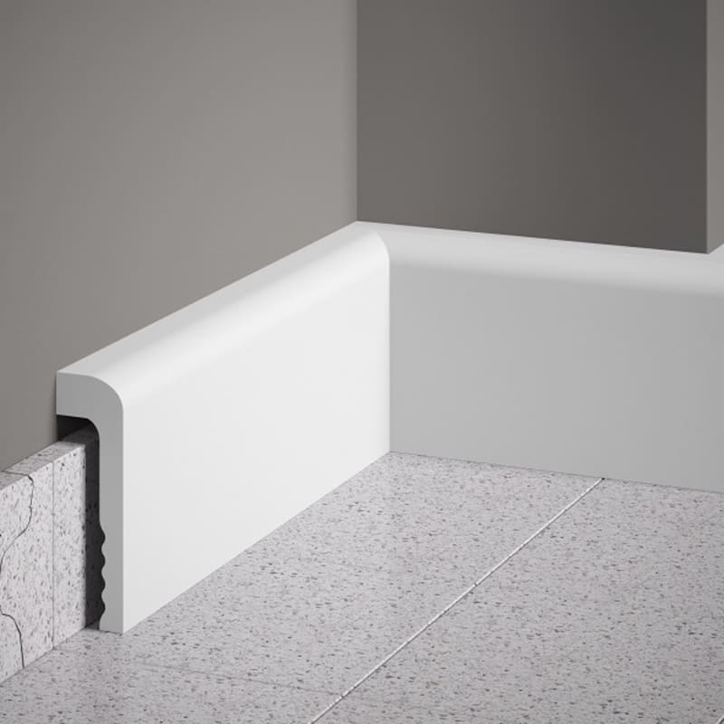 Rodapié blanco moderno de PVC instalado en esquina sobre suelo cerámico y pared gris.