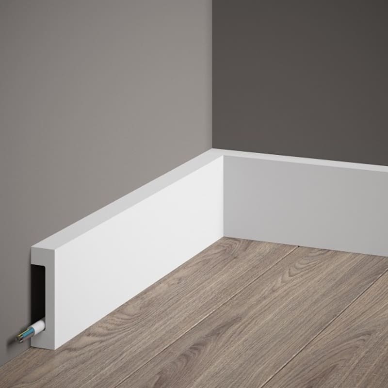 Rodapié blanco moderno con espacio para cables sobre suelo de madera en esquina interior