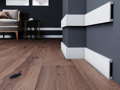 Rodapiés decorativos blancos en pared gris y suelo de madera, salón moderno elegante