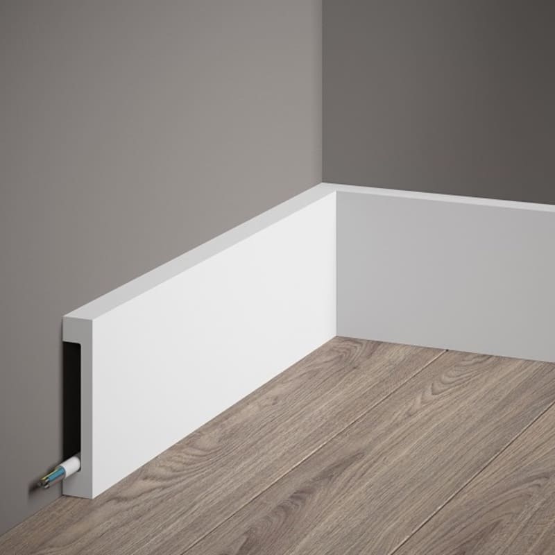 Rodapié blanco moderno para cables en esquina, suelo de madera, pared gris.