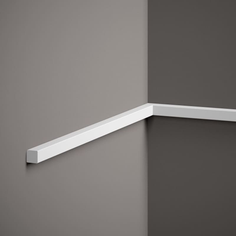 Moldura decorativa blanca de perfil recto instalada en esquina de pared gris