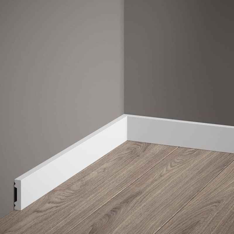 Rodapié blanco moderno en esquina de habitación con suelo laminado y pared gris
