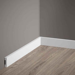 Rodapié blanco moderno en esquina de habitación con suelo laminado y pared gris