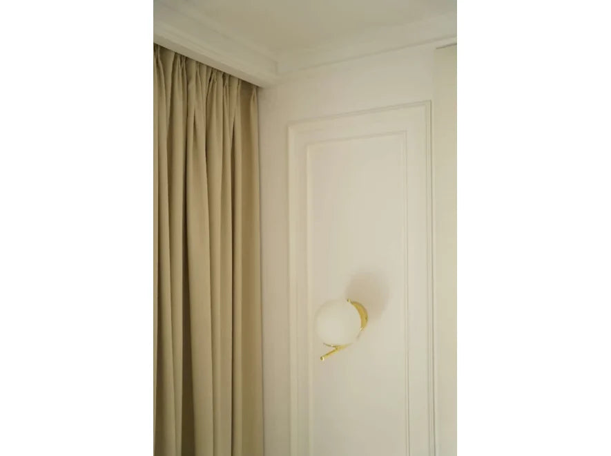 Moldura decorativa blanca en pared con aplique dorado y cortina beige