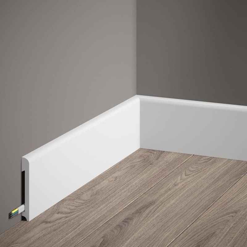 Rodapié blanco moderno en esquina, cubre cables, sobre suelo laminado gris claro