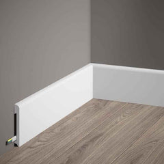 Rodapié blanco moderno en esquina, cubre cables, sobre suelo laminado gris claro