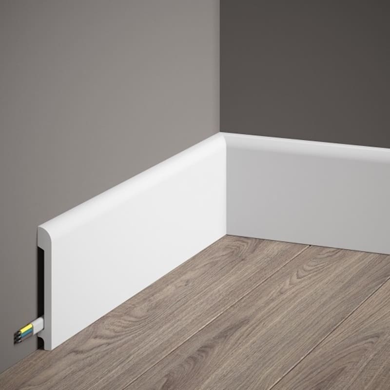 Rodapié blanco moderno con canaleta para cables en esquina de pared gris y suelo de madera clara.