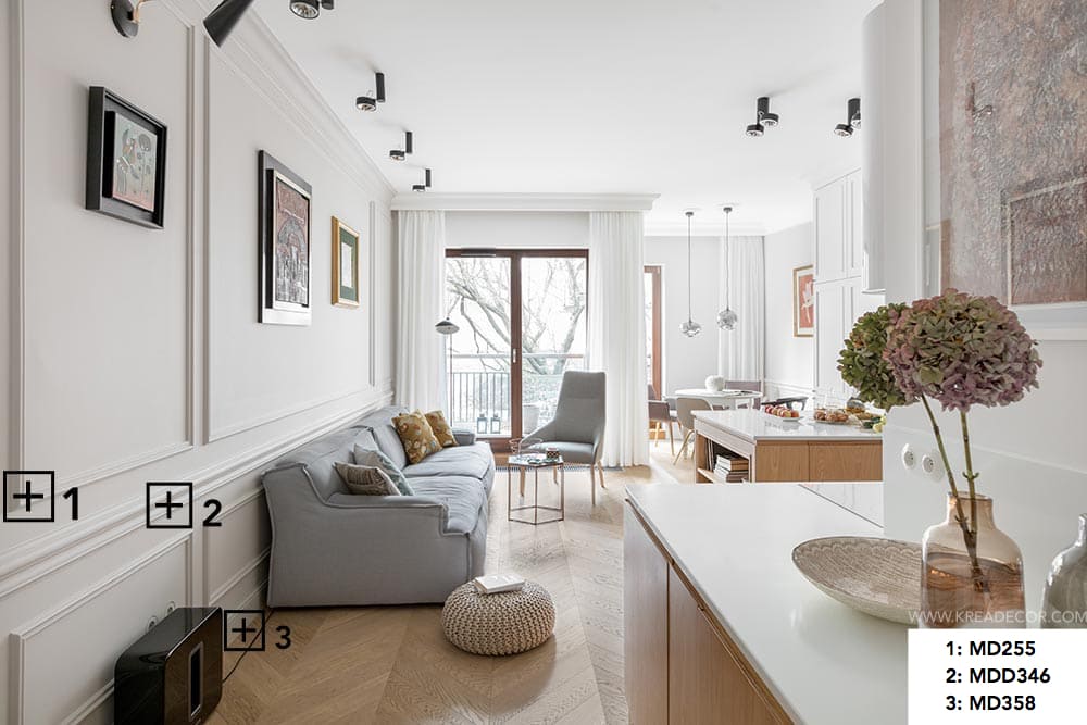 Salón moderno con molduras decorativas blancas y rodapié, sofá gris y luz natural