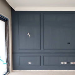 Pared azul oscuro con molduras decorativas y rodapiés blancos en interior moderno