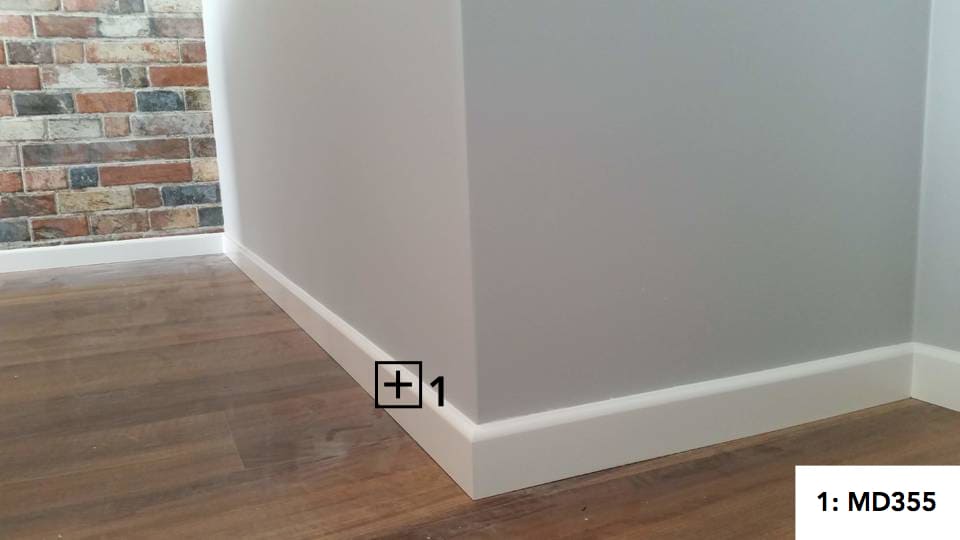 Rodapié blanco canto redondo instalado en un rincón de pared con suelo de madera