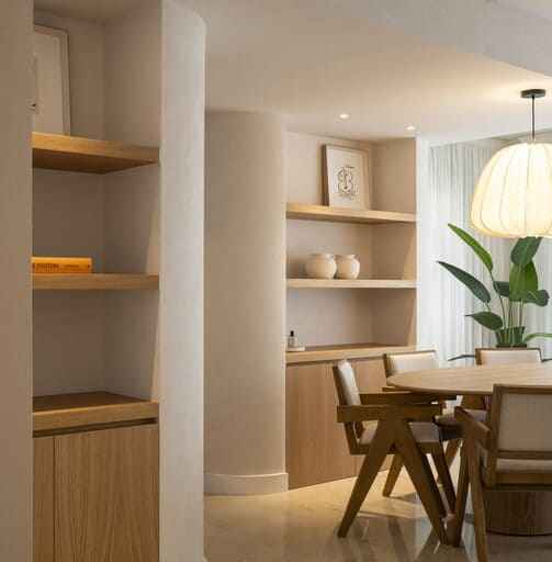 Comedor moderno con molduras decorativas, estantes de madera y luz natural, diseño elegante.