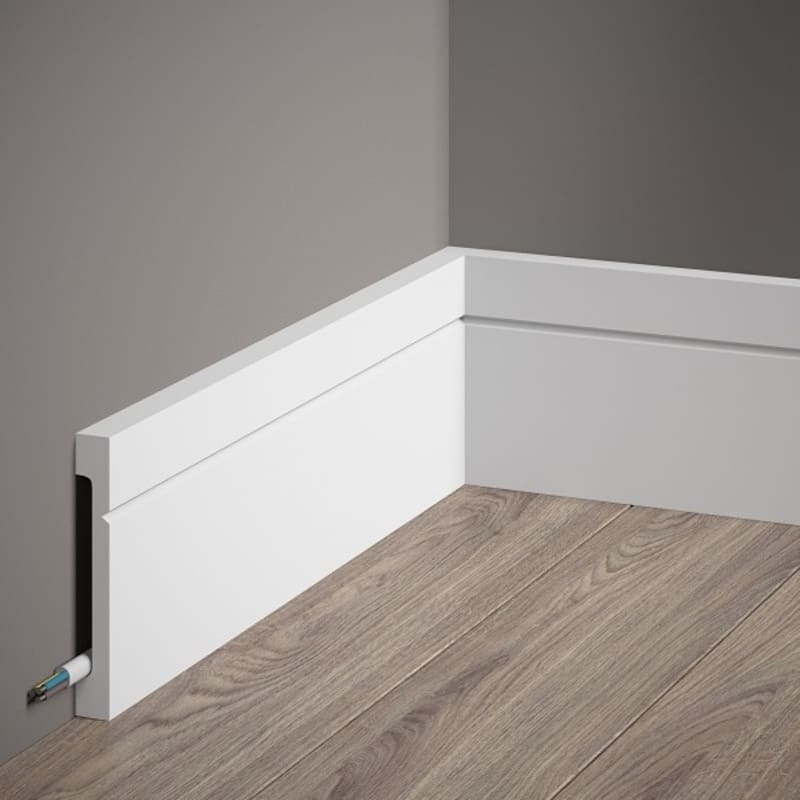 Rodapié blanco moderno para pared con canaleta para cables, sobre suelo de madera.