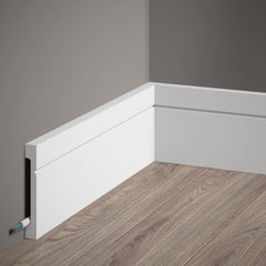 Rodapié blanco moderno para pared con canaleta para cables, sobre suelo de madera.