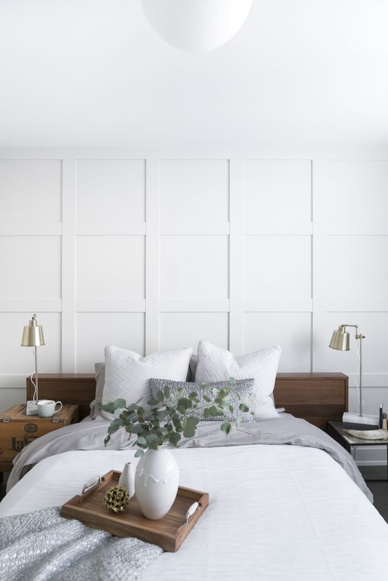 Dormitorio moderno con molduras decorativas blancas en la pared y cama de madera elegante