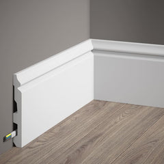 Rodapié blanco moderno con canaleta para cables en pared gris y suelo laminado.