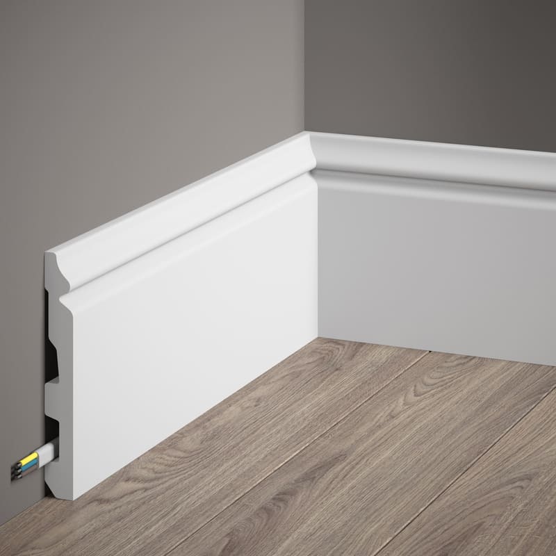 Rodapié blanco moderno con canaleta para cables en pared gris y suelo laminado.