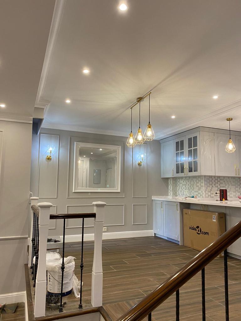 Sala moderna con molduras decorativas blancas, rodapiés altos y suelo de madera oscura.