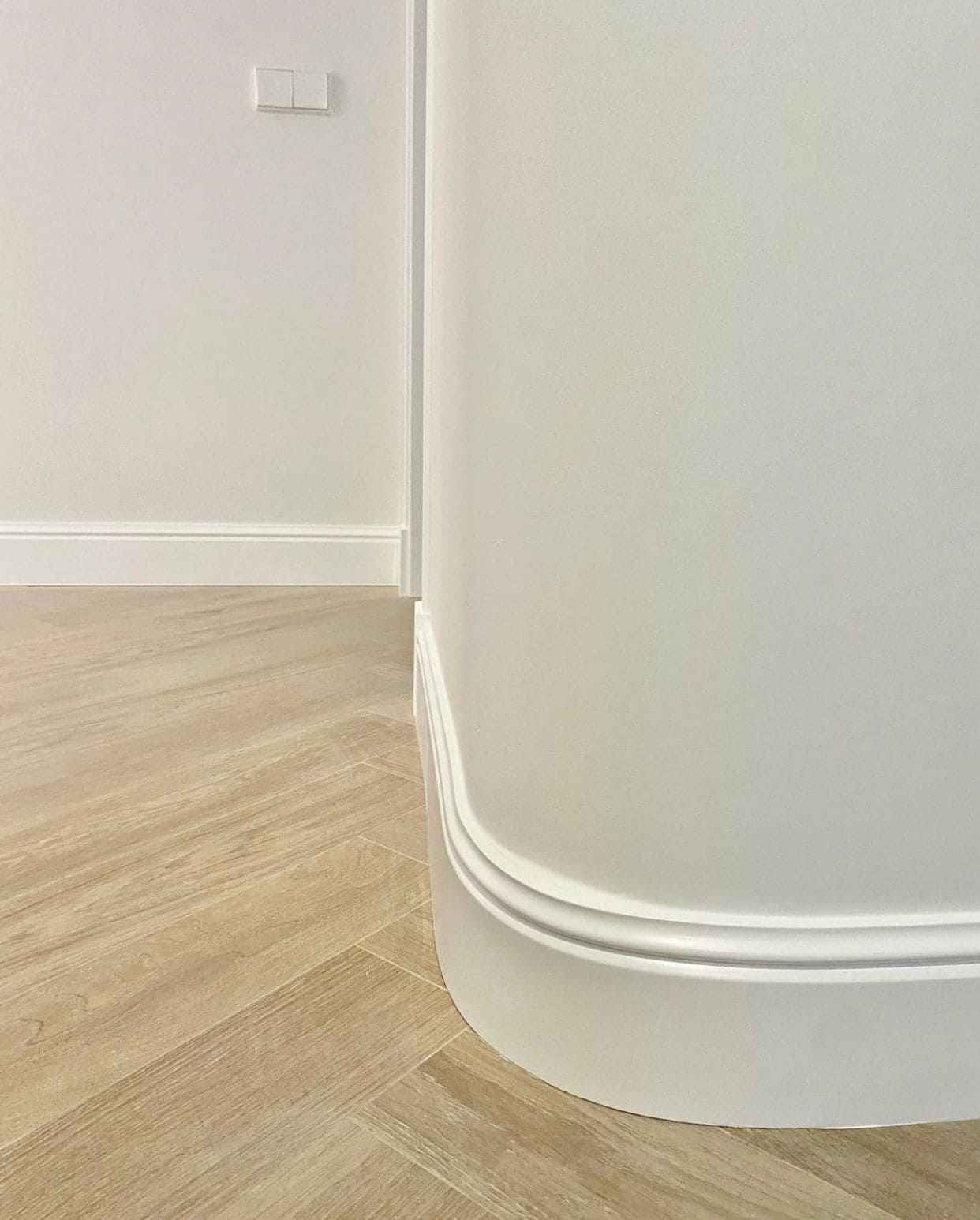 Rodapié blanco flexible en pared curva, suelo de madera, moldura decorativa moderna
