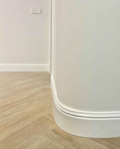 Rodapié blanco decorativo de PVC flexible en pared curva con suelo imitación madera