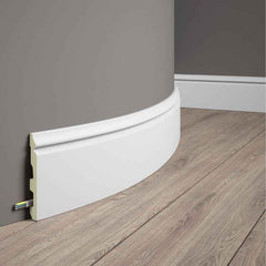 Rodapié flexible blanco para pared curva, ocultando cables, ideal para suelos de madera.