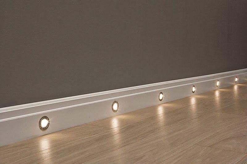 Rodapié blanco decorativo con luces LED integradas sobre suelo de madera clara