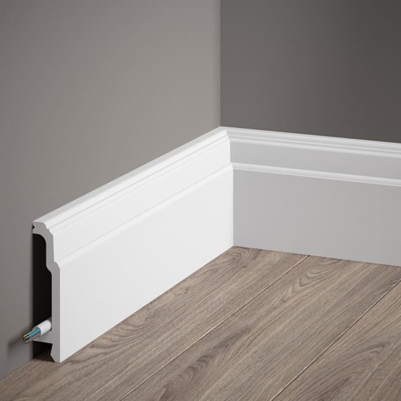 Rodapié blanco de diseño moderno con canal interno para cables, instalado en pared gris y suelo de madera.