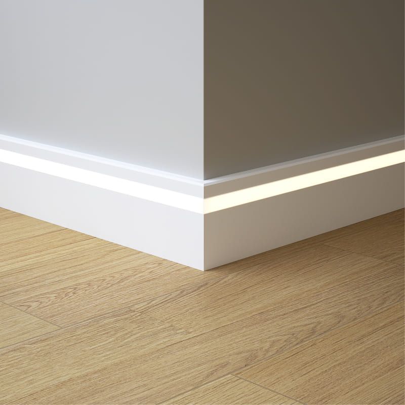 Rodapié blanco decorativo con luz LED en esquina de pared y suelo de madera clara