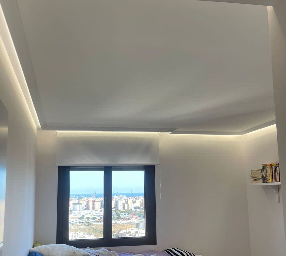 Techo moderno con moldura decorativa y luz LED indirecta en dormitorio luminoso