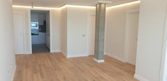 Sala moderna con suelo de madera, rodapiés blancos y molduras decorativas en techo