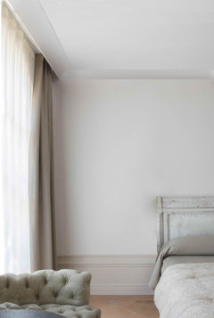Dormitorio elegante con moldura decorativa blanca, rodapié y cortinas largas beige