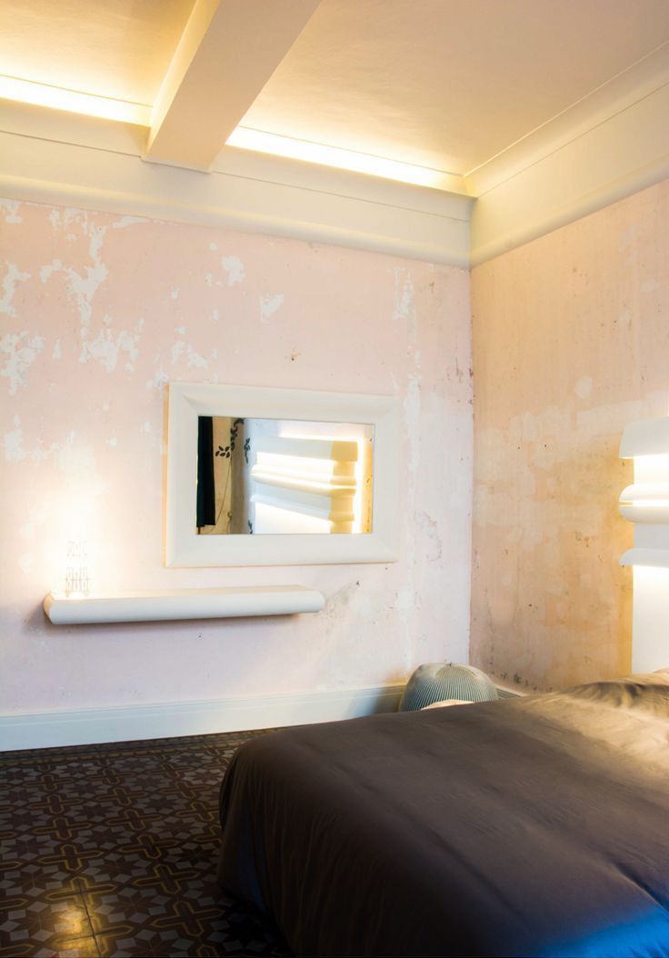 Dormitorio con molduras decorativas blancas, pared texturizada y espejo rectangular grande.