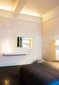 Dormitorio con molduras decorativas blancas, pared texturizada y espejo rectangular grande.