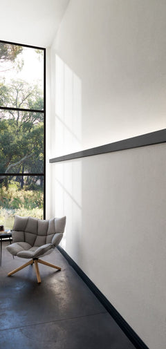 Moldura decorativa moderna en pared blanca de sala con ventana grande y silla gris