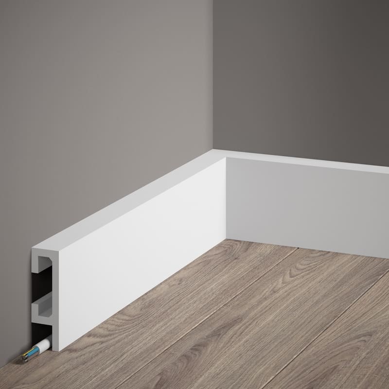 Rodapié blanco moderno con canaleta para cables en pared gris y suelo imitación madera.