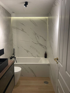 Baño moderno con bañera, paredes con acabado mármol y suelo imitación madera