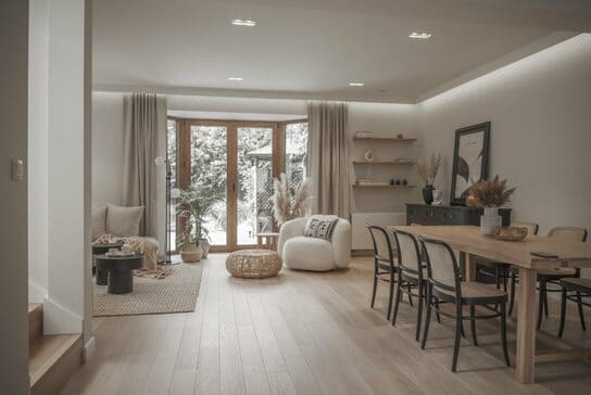 Salón comedor moderno con suelo de madera clara, molduras decorativas y muebles minimalistas.