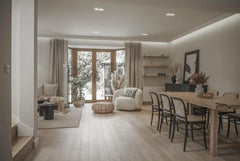 Salón comedor moderno con suelo de madera clara, molduras decorativas y muebles minimalistas.