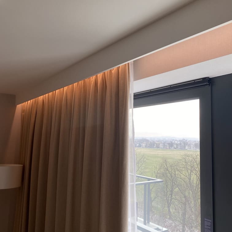Cornisa decorativa blanca con iluminación LED y cortinas en ventana moderna