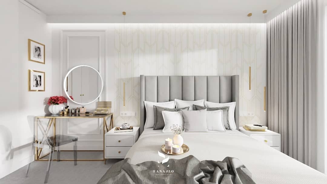 Dormitorio moderno con cabecero acolchado gris, molduras decorativas y mesa dorada elegante.